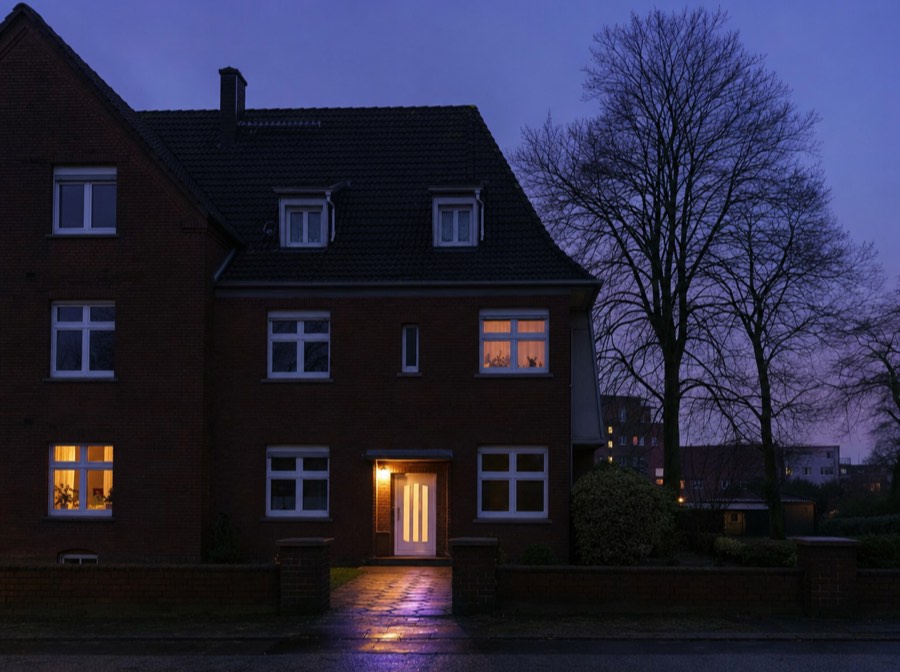 Beispielmotiv: Mehrfamilienhaus aus rotem Klinker in einer Wohnstraße in der Dämmerung